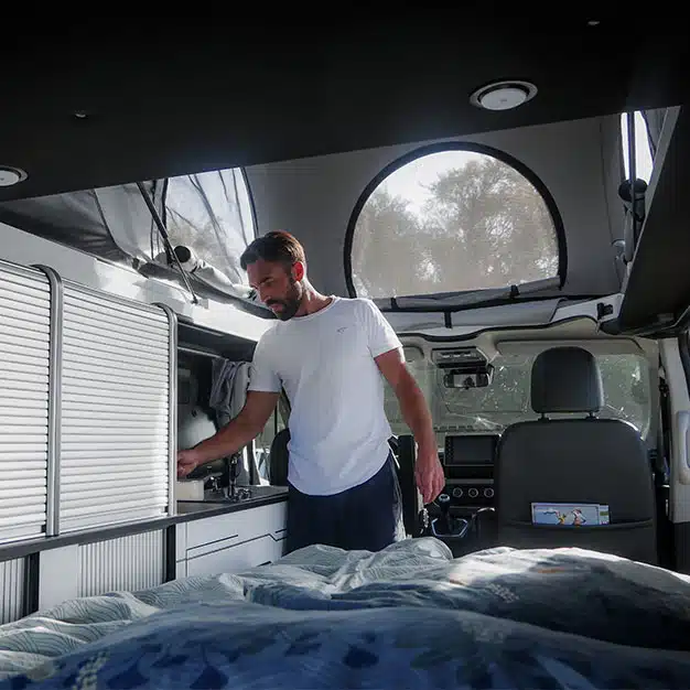 homme debout qui cuisine dans un van aménagé hanroad