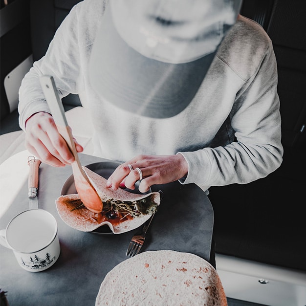 personne préparant un repas dans un van aménagé hanroad sur une table
