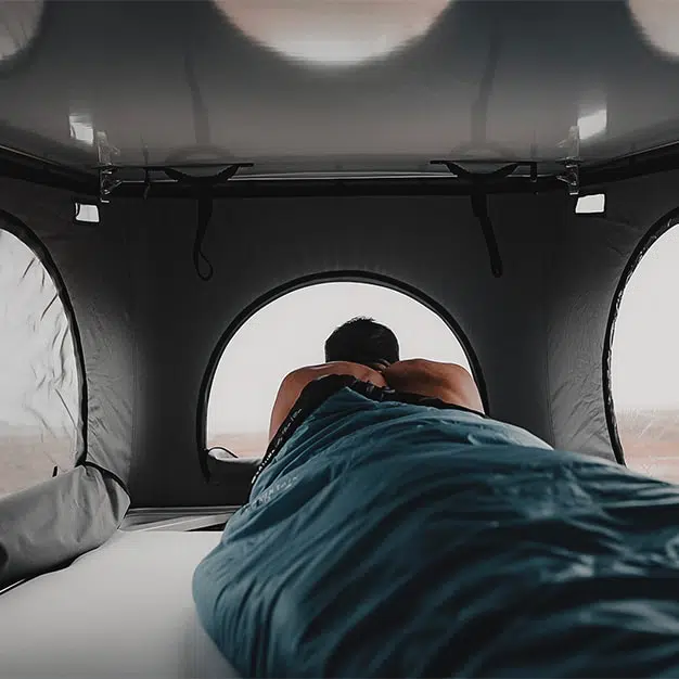 toit relevable avec trois ouvertures personne dormant dans un sac de couchage