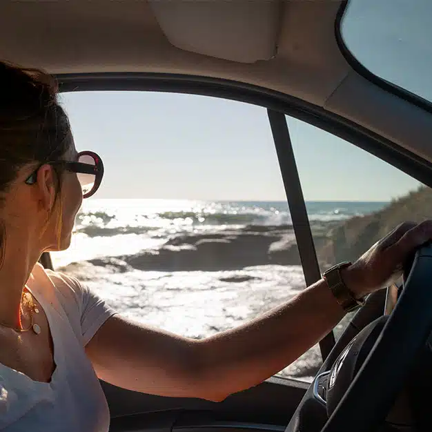 femme au volant d'un van aménagé hanroad le long de la mer