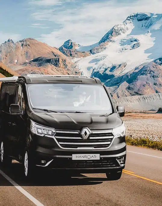 van aménagé de couleur noir hanroad sur porteur renault trafic roulant sur une route de montagne