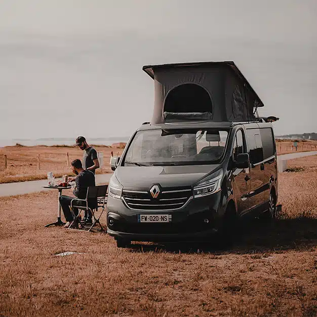 vanlifers déjeunant à côté d'un van aménagé hanroad sur porteur renault trafic avec toit relevé