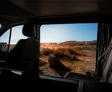 porte coulissante ouverte d'un van aménagé avec vue sur la plage