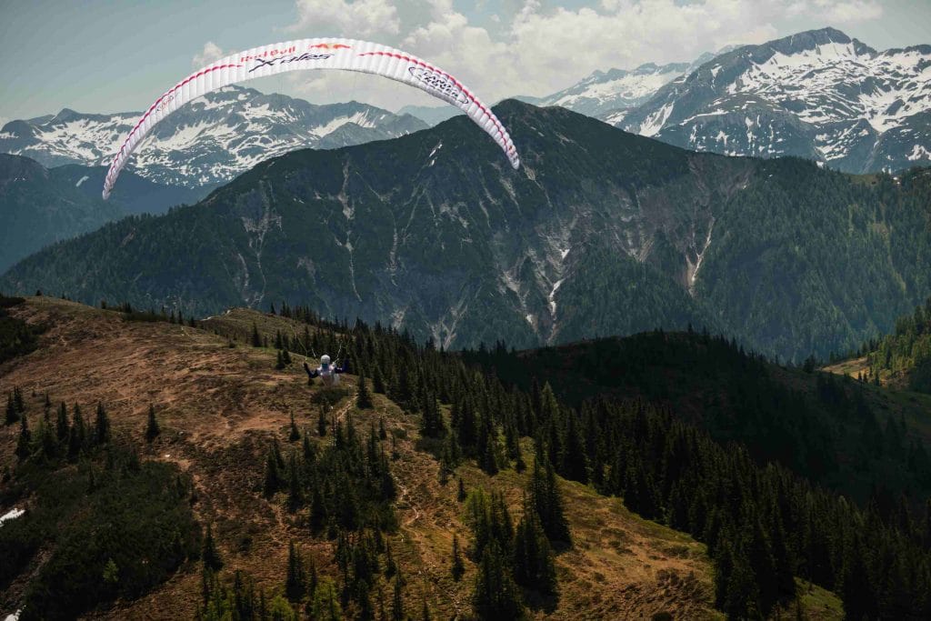 une parapentiste volant au-dessus de montagnes
