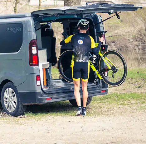triathlète mettant un vélo dans le coffre d'un van aménagé hanroad
