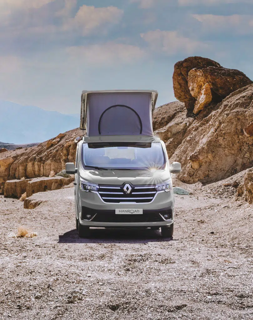 van aménagé hanroad gris avec toit relevé garé sur le sable dans un paysage désertique