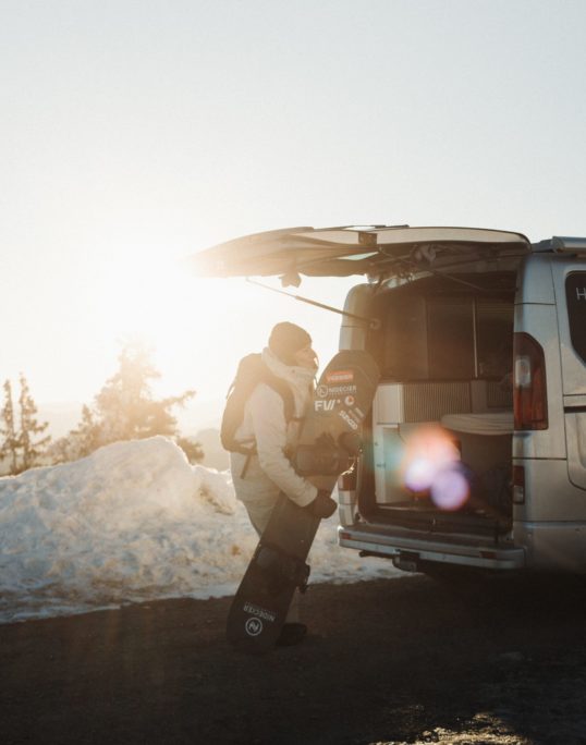 Tiphanie Perrotin range sa planche de snowboard dans son van aménagé Hanroad.