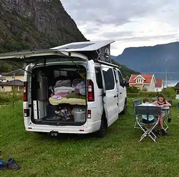 deux enfants assis autour d'une table à côté d'un van aménagé hanroad