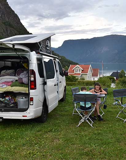 Une famille installée à l'extérieur du van aménagé en Norvège.