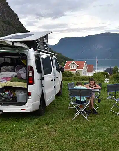 Une famille installée à l'extérieur du van aménagé en Norvège.