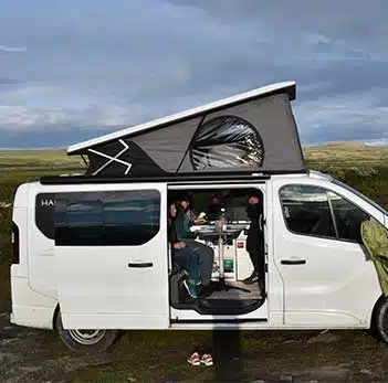 une famille déjeunant dans son van aménagé hanroad sur base renault trafic avec toit relevé