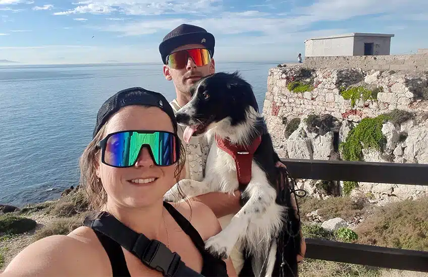 selfie d'un couple de vanlifers avec leur chien devant la mer