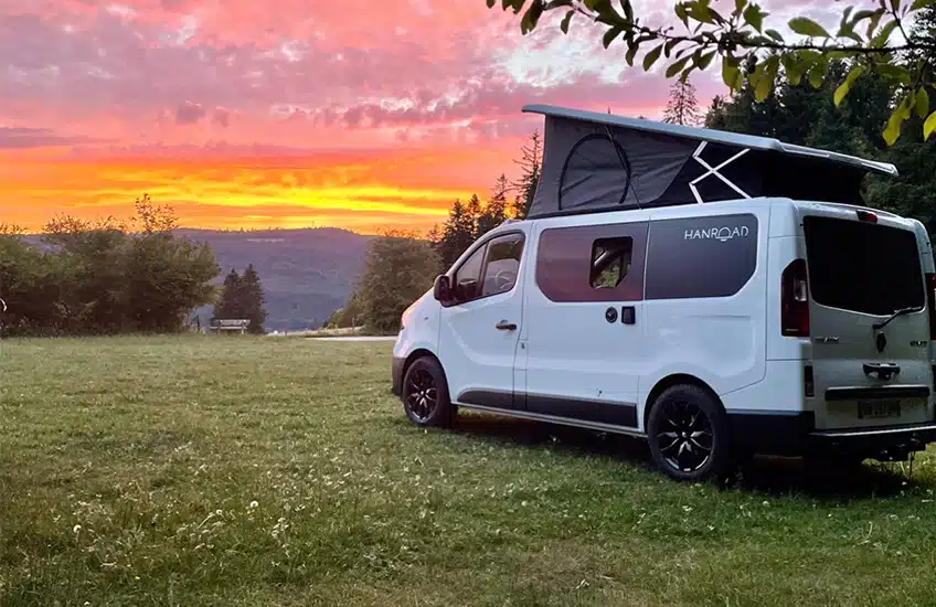 coucher de soleil devant un van aménagé blanc à toit relevable hanroad