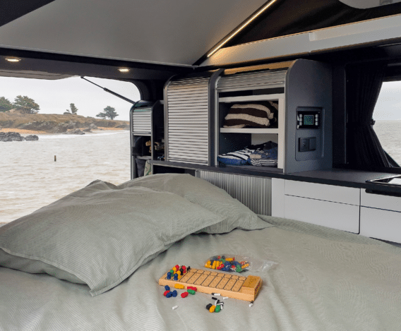 Banquette coulissante en configuration nuit dans le van aménagé avec vue sur la mer.