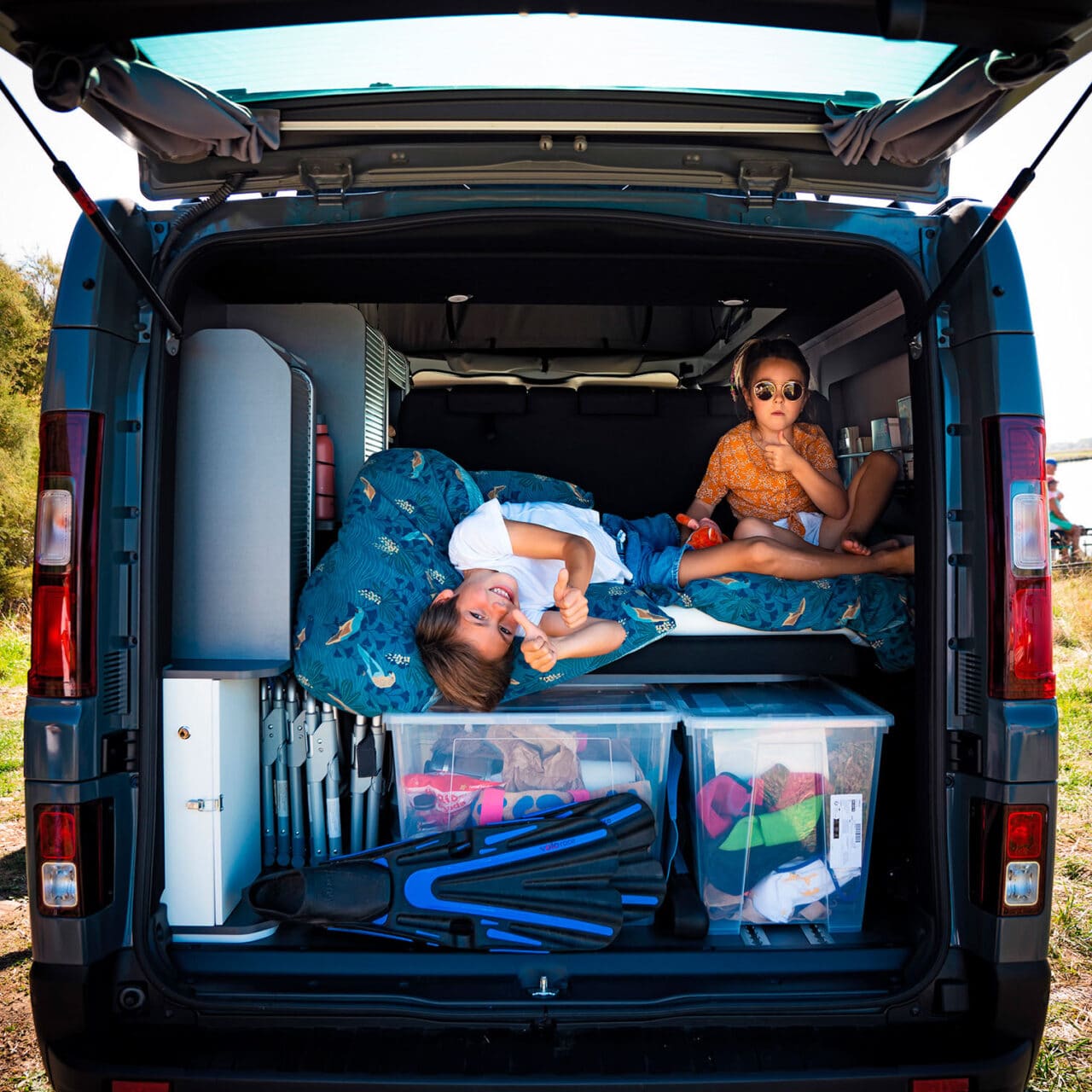Soute remplie d'affaires avec deux enfants pendant un road trip familial en van aménagé Hanroad.