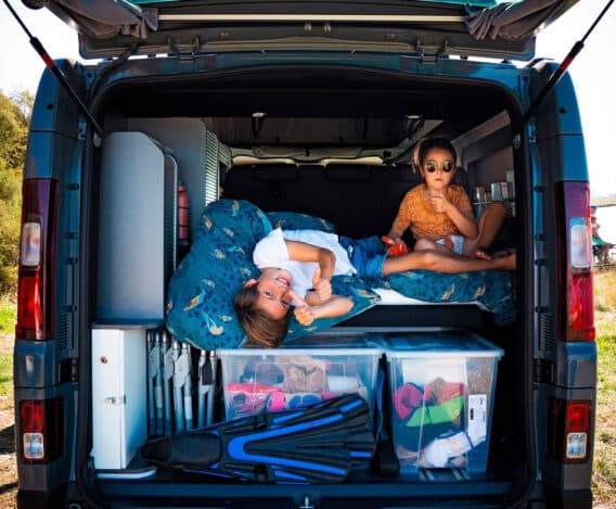 Soute remplie d'affaires avec deux enfants pendant un road trip familial en van aménagé Hanroad.