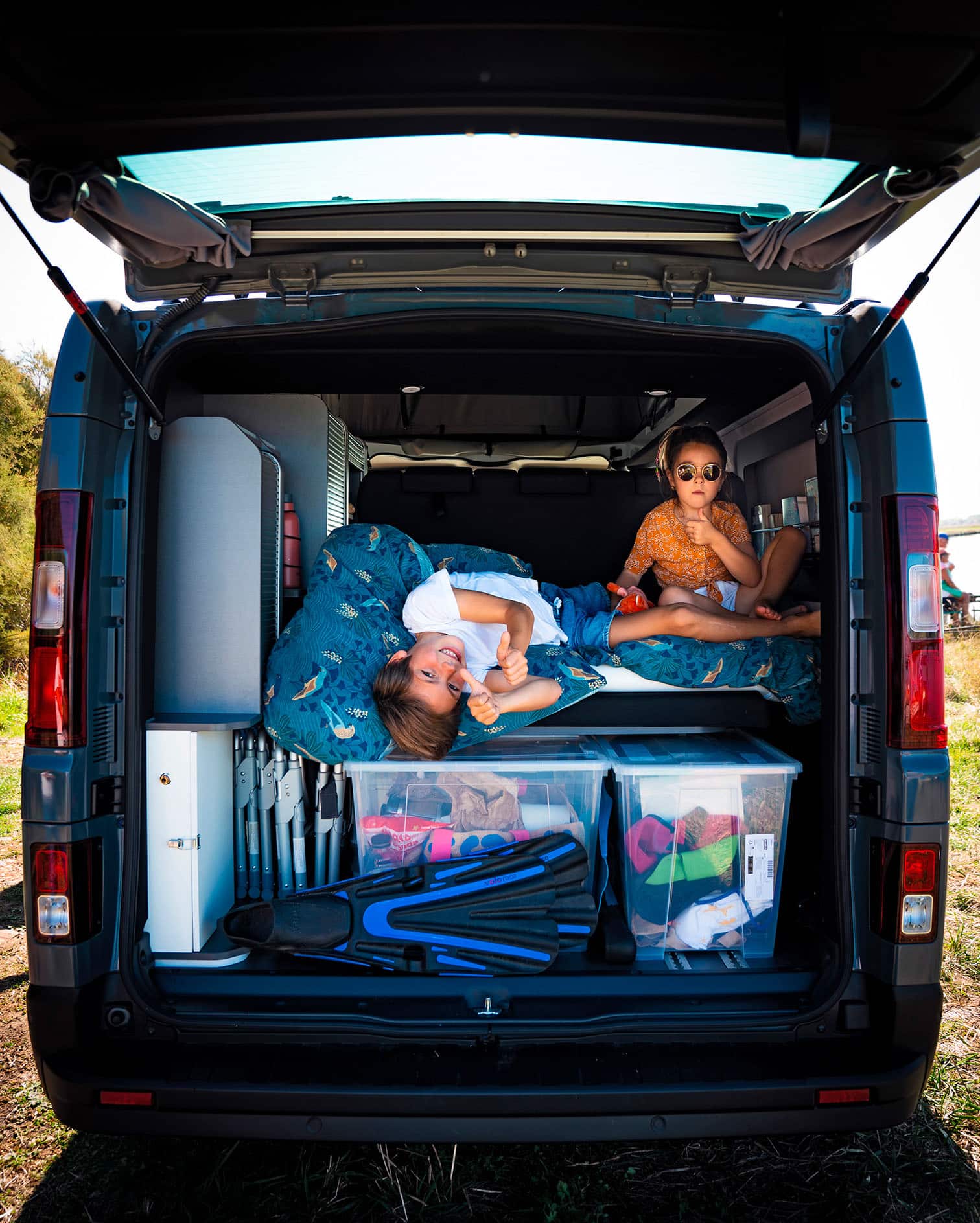 Soute remplie d'affaires avec deux enfants pendant un road trip familial en van aménagé Hanroad.