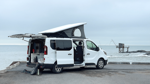 Van aménagé Hanroad avec toit relevable face à la mer.