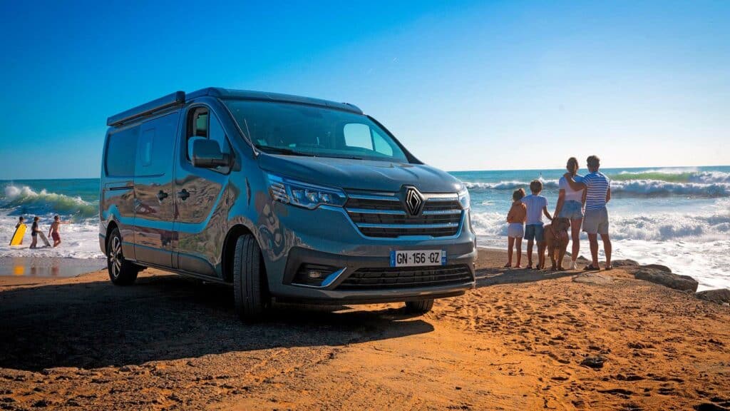 Un van aménagé Hanroad devant la mer avec une famille et un chien à côté.