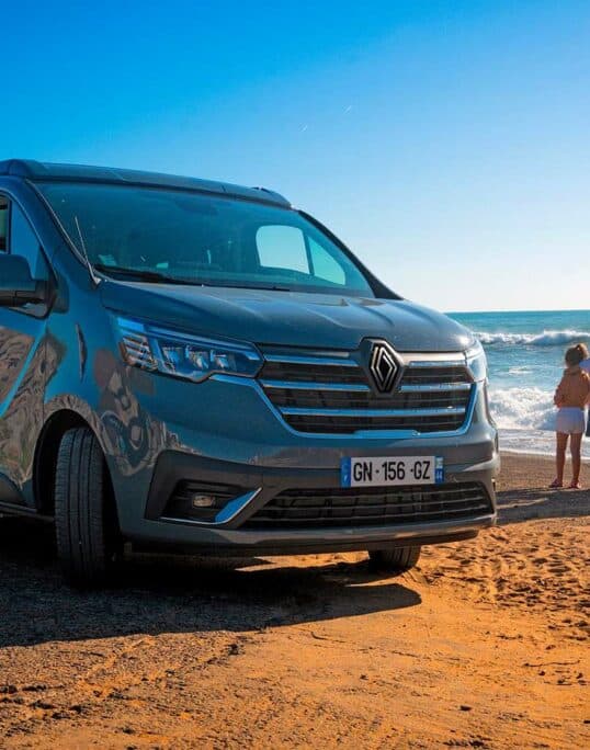 Un van aménagé Hanroad devant la mer avec une famille et un chien à côté.