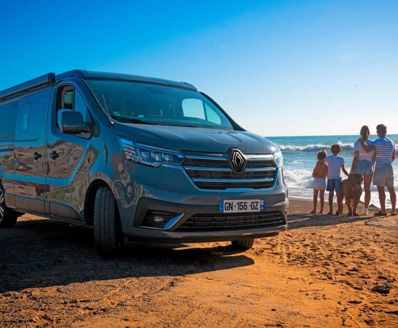 Un van aménagé Hanroad devant la mer avec une famille et un chien à côté.