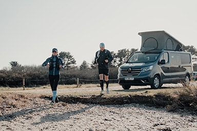 Couple de traileur en pleine sortie trail avec un van aménagé au second plan.