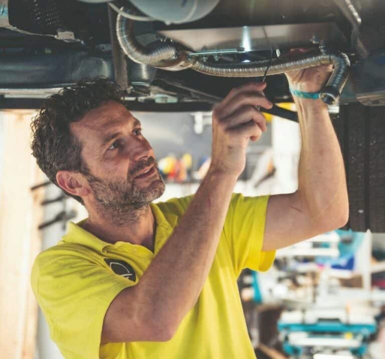 homme d'un atelier réparant un van aménagé